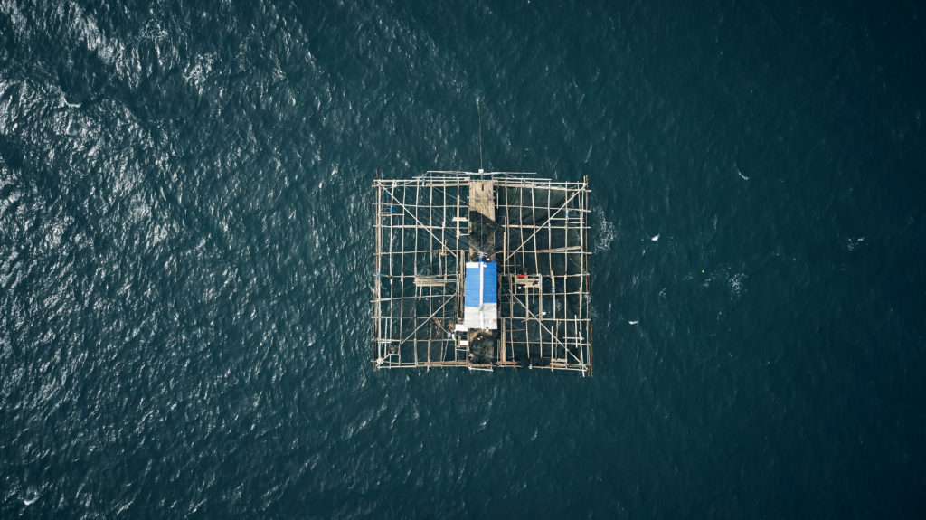 High angle shot of a built fishing structure floating in the middle of the ocean called a kelong.