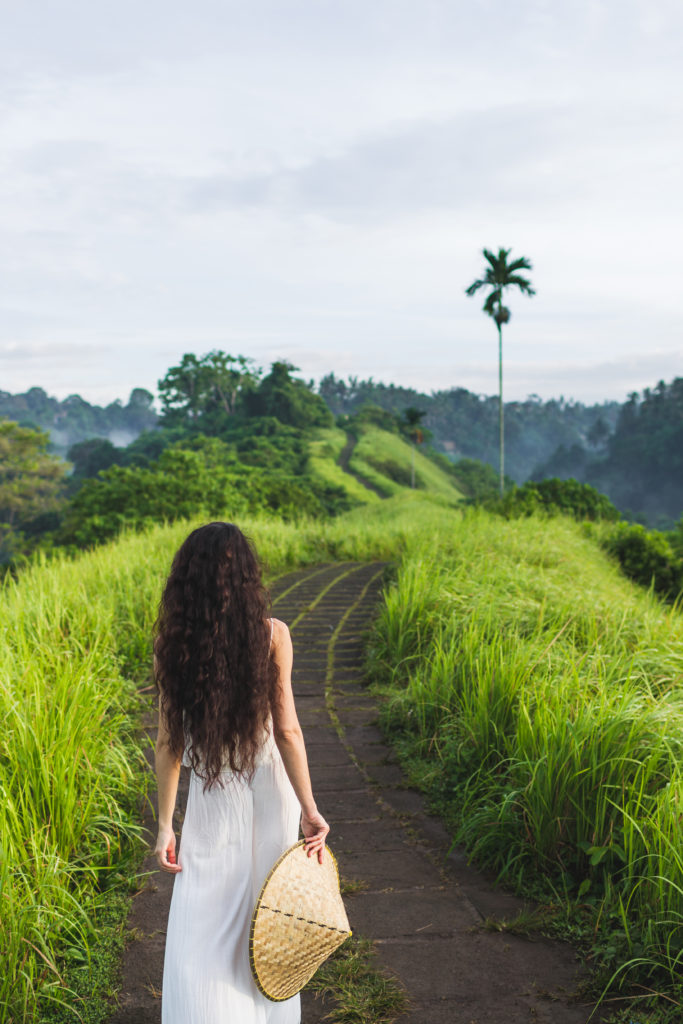 Young beautiful woman walking on Campuhan Ridge way of artists, in Bali, Ubud. Beautiful calm sunny morning